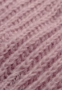 Zbliżenie na miękką, puszystą różową dzianinę, ukazujące szczegółową teksturę oraz splecione pętle włóczki.