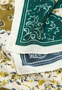 Trois tissus à motifs : un bandana vert avec un motif floral blanc, un bandana bleu marine, et un imprimé floral en jaune, rose et bleu.