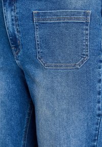 Tmavomodré džínsy z denimu s zadným vreckom s kontrastným šitím a textúrovaným povrchom zdôrazňujúcim tkanie látky.