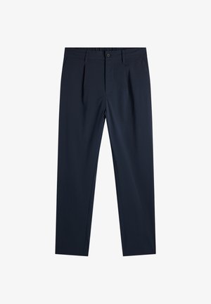 Laivastonsiniset räätälöidyt housut, joissa on laskokset, vyölenkit, edessä nappikiinnitys ja pieni metallilogo oikeassa taskussa.
