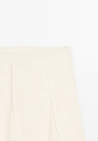 Jupe crème taille haute avec coutures frontales et forme évasée en A, présentée sur un fond blanc.