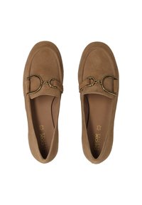 Mocasines de ante marrón con punta redondeada, que presentan un adorno de metal dorado en la parte delantera. Textura suave y plantillas acolchadas.