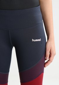 Granatowe i winne legginsy sportowe z wysokim stanem, o gładkiej fakturze, z logo hummel z przodu.
