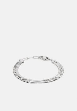 Pulsera de cadena de plata con un patrón de espiga, enlaces planos y un cierre seguro. Textura suave y acabado metálico pulido.