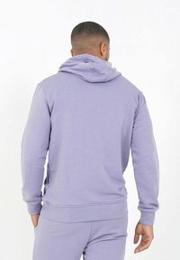 Sudadera morada hecha de un tejido suave, con capucha ajustable, puños y dobladillo acanalados, con un corte holgado y hombros sin costuras.