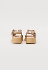 Sandales de couleur bronze avec un dessus texturé, deux larges brides et une semelle plateforme épaisse beige. Détail de boucle au niveau de la cheville.