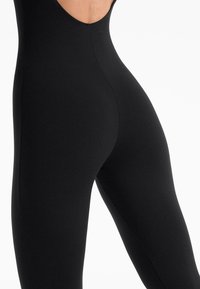Body negru cu un decolteu în formă de U adânc. Material neted și elastic, cu un design ajustat, cusături minime și fără hardware vizibil.