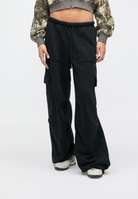 Μαύρο cargo παντελόνι από μαλακό ύφασμα, με μεγάλα πλαϊνά τσέπες, άνετη εφαρμογή και ρυθμιζόμενη μέση με κορδόνι.