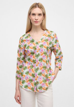 Bluse mit Blumenmotiv, die einen V-Ausschnitt, 3/4-Ärmel, helle Farben (Pink, Grün, Orange) und einen leichten, durchsichtigen Stoff hat.