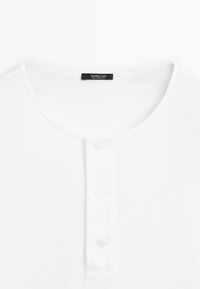 Weißes Henley-Shirt mit Rundhalsausschnitt, drei Knöpfen an der Knopfleiste und "Massimo Dutti"-Etikett im Kragen.