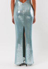 Un abito da sera aderente e senza schienale di colore azzurro chiaro, decorato con paillettes, con uno spacco alto che si estende dall'orlo fino a metà coscia.