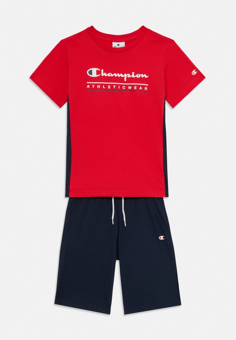 Crvena majica kratkih rukava s logotipom "Champion Athleticwear" i tamnoplave kratke hlače s elastičnom gumicom i logotipom sa strane.