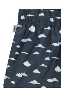 Shorts scuri in tessuto con un motivo a nuvole blu chiaro. Presentano un elastico in vita e un'etichetta con la scritta "Pookies". Texture liscia.