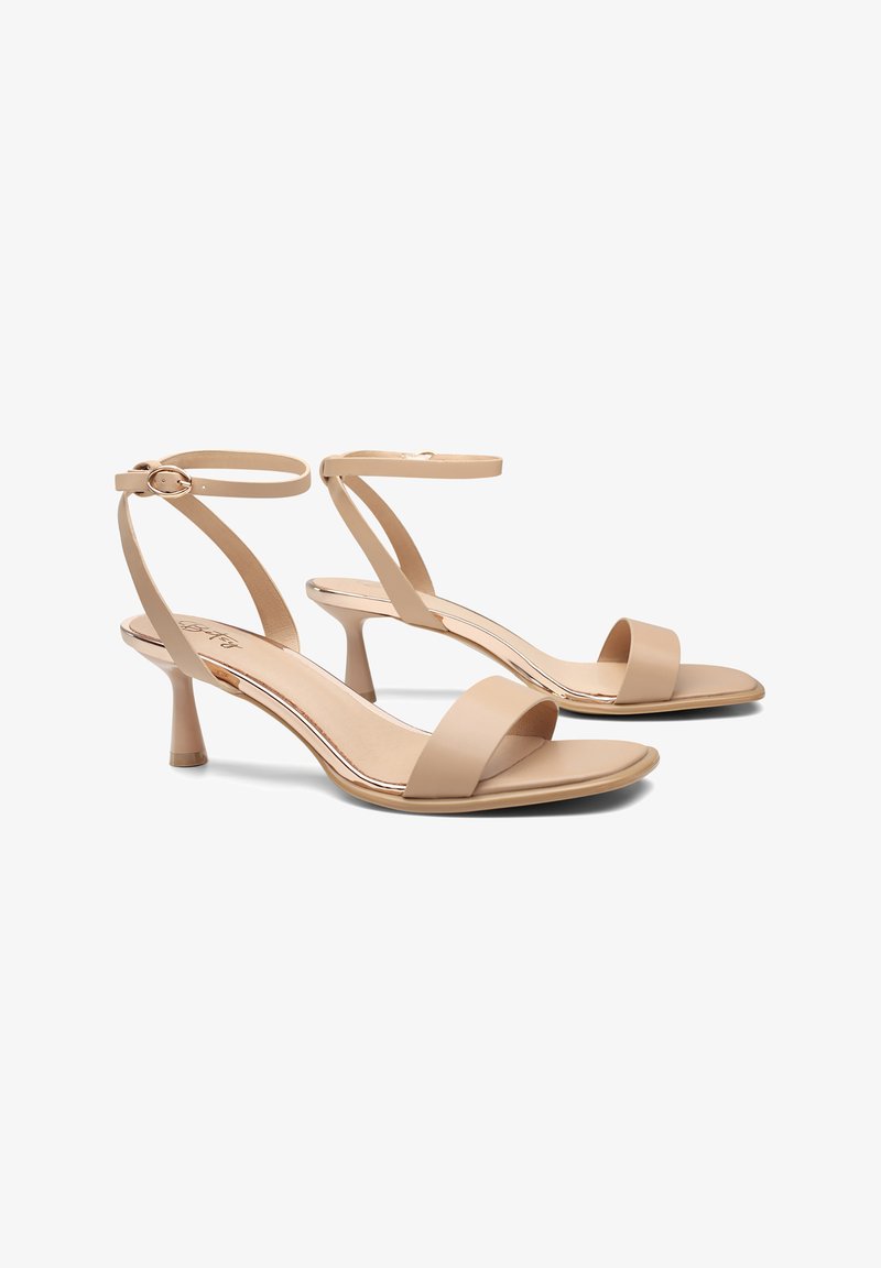 Sandalias de tiras beige con una banda frontal ancha, correa ajustable en el tobillo y un tacón de altura media con acabado suave.