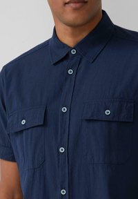 Kurzarmhemd in Marineblau aus strukturiertem Stoff, mit zwei Brusttaschen und hellblauen Knöpfen. Mit strukturiertem Kragen und durchgehender Knopfleiste.