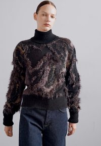 Pulover turtleneck negru cu un model fuzzy, texturat, în nuanțe de maro și accente de fir metalic. Mâneci lungi și croială casual.