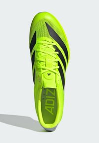 Neon yellow athletic shoe with black stripes, textured upper, and flat laces. Features a cushioned interior and logo on the insole.