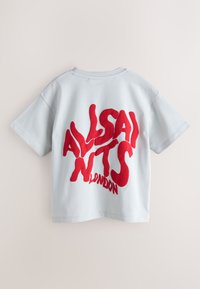 Lyseblå bomulds-T-shirt med fed, uregelmæssig rød tekst, der lyder "ALLSAINTS LONDON" på ryggen. Korte ærmer og afslappet pasform.