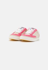 Sneakers in tela rosa e beige con lacci bianchi, suole in gomma e finitura testurizzata. Presentano una punta arrotondata e accenti a contrasto.