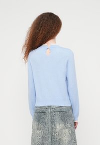 Ανοιχτό μπλε πλεκτό πουλόβερ με στρογγυλή λαιμόκοψη διακοσμημένη με δαντέλα και μικρή οπή στην πλάτη. Μακριά μανίκια και εφαρμοστό τελείωμα.