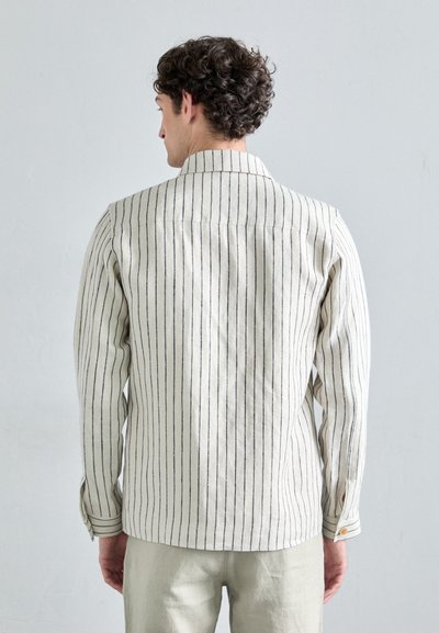 Chemise en lin rayé en crème avec des rayures verticales sombres, design avec col, poignets boutonnés et coupe décontractée.