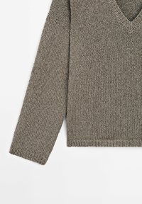 Pull en maille col en V de couleur marron atténuée avec une coupe ample. Il présente des manches longues et un motif en maille texturée.