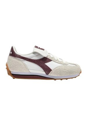 Zapatilla de ante blanca y beige con franja lateral texturizada en color granate, cordones delanteros, tira de velcro y suela de goma marrón con tacos de agarre.