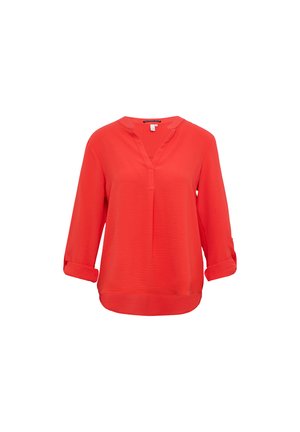 Blouse rouge à manches longues avec un col en V et des poignets retroussés, présentant un tissu texturé et un ourlet légèrement arrondi.