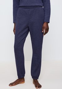 Marina ribbade stickade sweatpants med elastisk midja och samlade vristhalsar, designade för komfort och avslappnad stil. Texturerad tyg synlig.