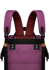 Lila Stoff-Rucksack mit breiten, gepolsterten Trägern in Burgundy, schwarzen Akzenten und einem strukturierten Lederdetail. Verstellbare Hardware enthalten.