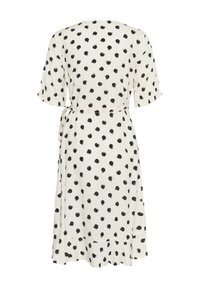 Gaun lengan pendek terbuat dari kain putih dengan polka dot hitam. Memiliki desain menyelubungi, ikat pinggang di pinggang, dan hem berkerut di bagian bawah.
