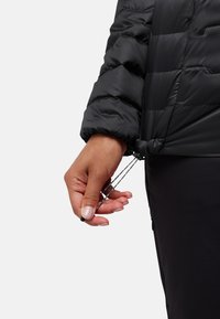 Zwarte gewatteerde jas met een gestructureerde afwerking, elastische manchetten en verstelbare trekkoorden aan de onderkant voor een aanpasbare pasvorm.