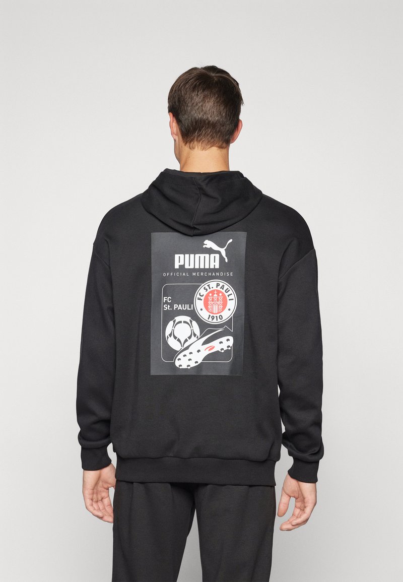 Felpa con cappuccio nera caratterizzata da una grafica con un pallone da calcio e una scarpa da calcio, marchiata con testo Puma e FC St. Pauli. Tessuto morbido e testurizzato.