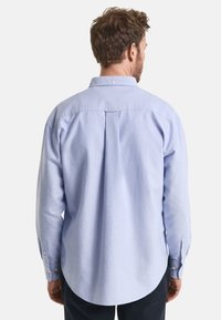 Hellblaues Button-up-Hemd mit einer Rückenfalte, rundem Saum und langenÄrmeln. Der Stoff wirkt weich mit einer leichten Textur. Klassisches Kragen-Design.