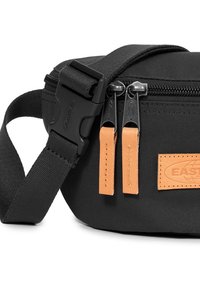 Sac banane en tissu noir avec deux zips métalliques et tirettes de zip en cuir beige, doté d'une sangle noire réglable avec boucle en plastique.