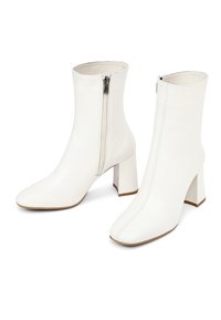 Bottes blanches au niveau de la cheville avec un bout pointu, texture en cuir lisse, fermeture éclair sur le côté et talons blocs. Design minimaliste avec des coutures verticales.