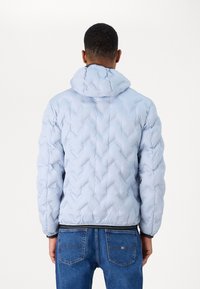 Giacca puffer blu chiaro con cappuccio, caratterizzata da una trapuntatura a chevron, polsini elasticizzati e un bordo nero all'orlo. Design informale con una vestibilità comoda.