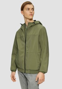 Olivgrüne Kapuzenjacke mit einem Frontreißverschluss, seitlichen Taschen und elastischen Bündchen. Glatter Stoff mit strukturierten Nähdetails.