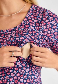 Vestido azul marino con estampado floral de pequeñas flores rosas y azules; cuenta con una abertura de bolsillo discreta debajo del escote para mayor accesibilidad.