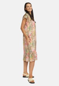Blommig midiklänning i lätt tyg med utsvängd nederdel, i mjuka rosa och gröna nyanser, korta ärmar och avslappnad passform.