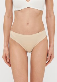 Nahkse sileda tekstuuri ja madala lõikega nõudev aluspüksipaari. Omab lihtsat vöökohta ja minimaalset katvust.