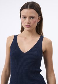 Top senza maniche blu navy con scollatura a V, caratterizzato da un motivo a coste testurizzato. Il materiale appare morbido e elasticizzato.