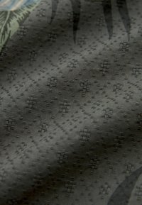 Tejido texturizado en gris oscuro que presenta un patrón diagonal de formas geométricas en relieve, creando un efecto visual sutil pero distintivo.