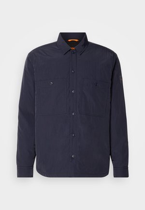 Tamsiai mėlynas mygtukų užsegimas marškiniai, pagaminti iš lengvos medžiagos, turintys dvi kišenes su užlenkimais, klasikinį apykaklę ir oranžinį akcentą ant iškirpės.