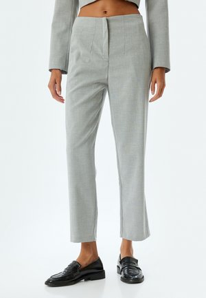 Grijze op maat gemaakte pantalons met een rechte snit en plooien, met een soepele textuur en een subtiel patroon. Gepaarde met zwarte loafers.
