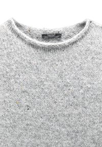 Jasnoszary sweter z dzianiny z okrągłym dekoltem, teksturowaną tkaniną i kolorowymi kropkami na całej powierzchni. Etykieta widoczna przy szyi.