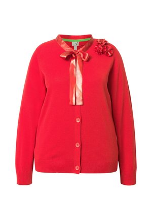 Rode button-up cardigan met satijnen striksluiting bij de kraag en drie stoffen bloemversieringen op de linkerschouder.