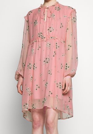 Rosa, durchscheinendes langärmliges Kleid mit Blumenmuster, Rüschendetails, einer Schleifenbinde am Ausschnitt und einem Saum mit unterschiedlicher Länge, getragen von einer Person vor einem schlichten Hintergrund.