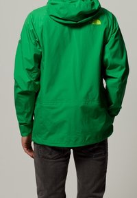 Grüne wasserdichte Jacke mit Kapuze, mit strukturiertem Finish, verstellbaren Bündchen und Branding an der oberen Rückseite und dem Ärmel.