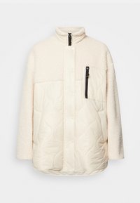 Puffig crema jacka med fleece övre del och kviltad nedre sektion. Har en dragkedja bröstficka och tryckknappar. Mjuk textur.